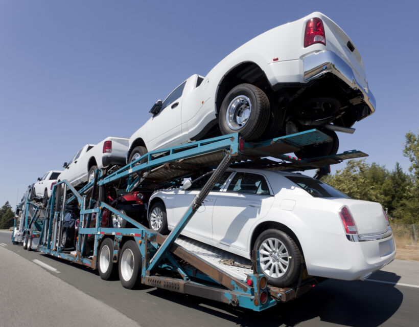 Rear view of trailer of new cars and trucks speeding to market.
