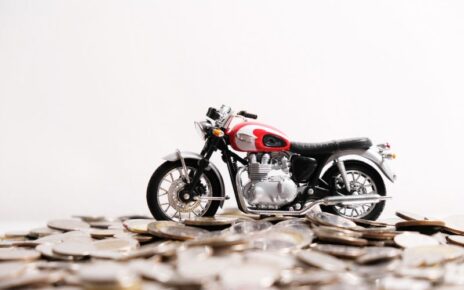 Modern classic motorcycle model on many of coins background, Finance concept.