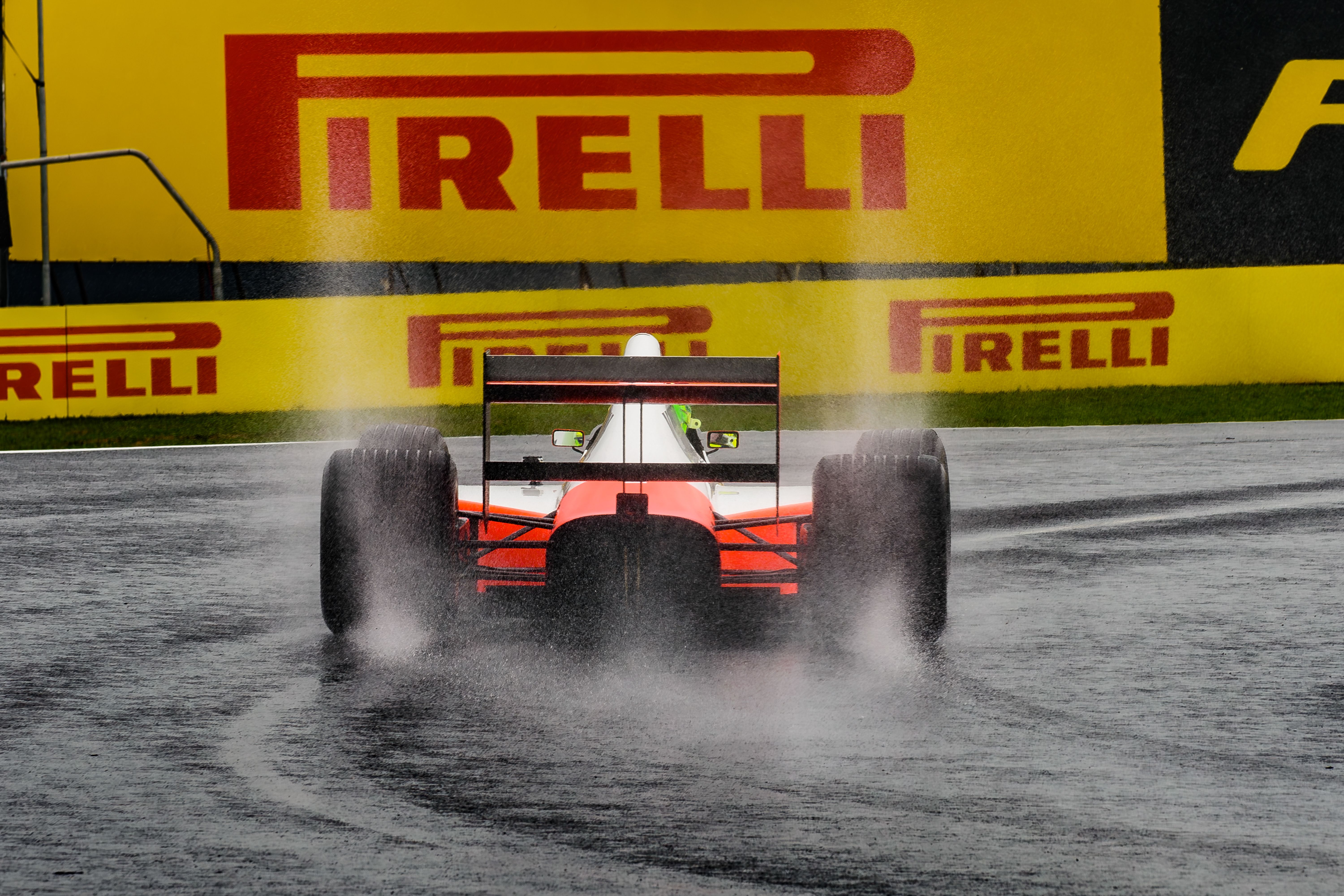 Formula One car splashing through a wet track under a Pirelli sign, illustrating tire technology and wet-weather racing performance